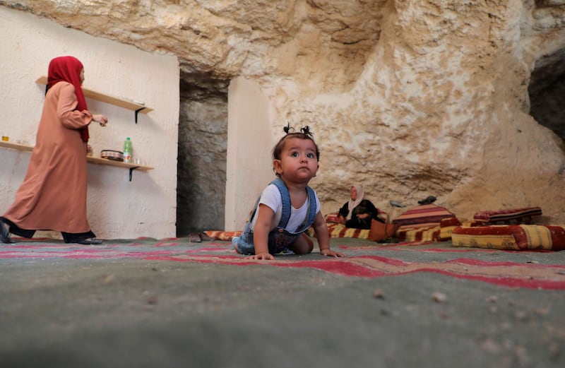 Ahmed Amarneh's daughter crawls across the carpeted floor of his home in a cave. AFP