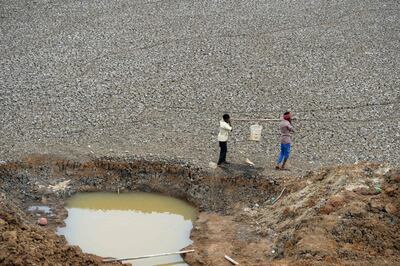 In this photo taken on June 20, 2019, Indian workers carry the last bit of water from a small pond in the dried-out Puzhal reservoir on the outskirts of Chennai. The drought is the worst in living memory for the bustling capital of Tamil Nadu state, India's sixth largest city, that is getting less than two thirds of the 830 million litres of water it normally uses each day.  - To go with 'INDIA-ECONOMY-WATER,FOCUS' by Alexandre MARCHAND
 / AFP / ARUN SANKAR / To go with 'INDIA-ECONOMY-WATER,FOCUS' by Alexandre MARCHAND
