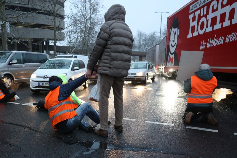 A pedestrian tries to drag a climate activist blocking a road in Berlin. AP