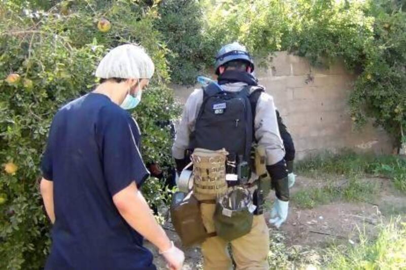 A UN chemical weapons expert (right) gathers evidence at one of the sites of an alleged poisonous gas attack in the southwestern Damascus suburb of Mouadamiya.