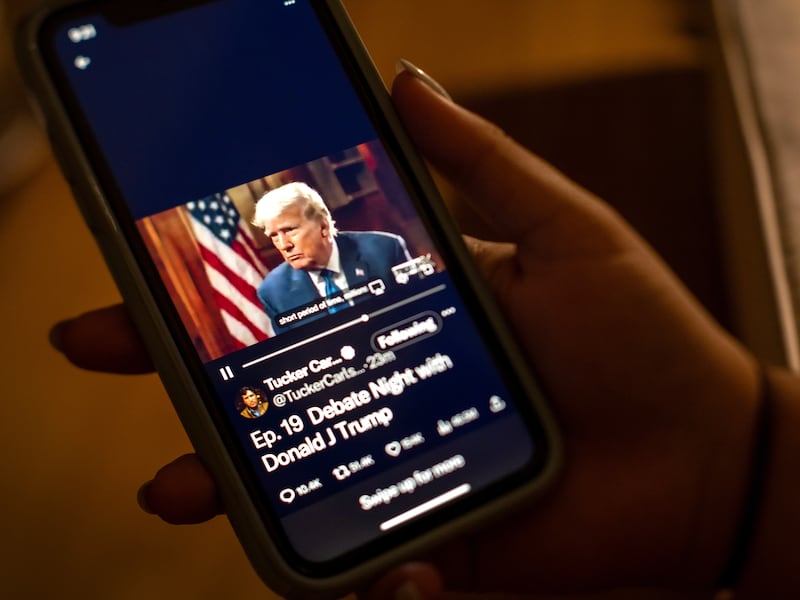 A viewer watches former president and current Republican candidate Donald Trump's interview with Tucker Carlson on the social media platform X. EPA