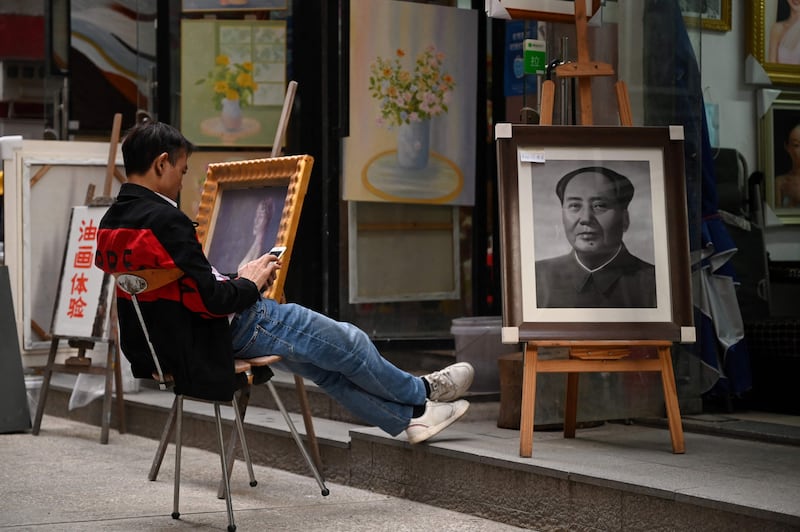 A man sits outside an art studio in Dafen. Local artists are adapting their styles and making the most of a booming domestic art market