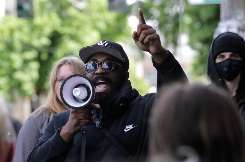 A man speaks into a megaphone during a,protest outside the Seattle Police Department East Precinct building. AP Photo