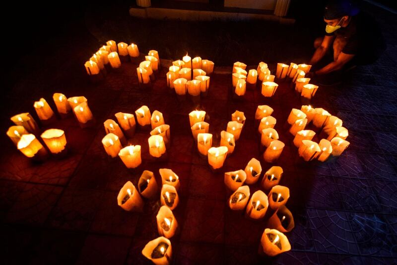A volunteer arranges candles to read "Fight Covid-19" during the Earth Hour near a Catholic church in Borongan City in Eastern Samar province on March 28, 2020. AFP
