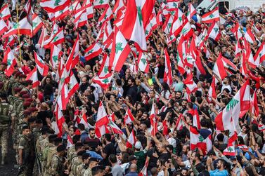 Protesters stand with Lebanese national flags before Lebanese army soldiers along the side of the Beirut-Jounieh highway in the northern Beirut suburb of Jal el-Dib amidst on the seventh day of protest against tax increases and official corruption, on October 23, 2019. The almost one-week-old massive street protests in Lebanon, sparked by a tax on messaging services such as WhatsApp, have morphed into a united condemnation of a political system seen as corrupt and beyond repair. / AFP / -