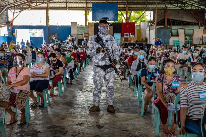 A soldier stands guard as people who lost their jobs during the pandemic queue for $20 cash aid in Manila, Philippines. About 24 million people in Manila and nearby provinces are under strict lockdown, the longest in the world. The Philippines has recorded more than 813,000 cases of Covid-19 so far, with nearly one in four people tested returning a positive result. Getty