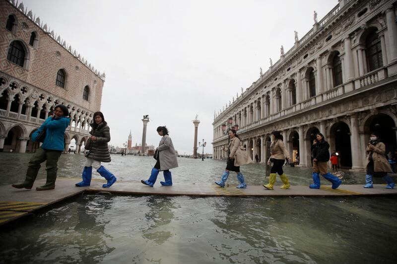 People use trestle bridges to walk in a flooded St. Mark's Square at Venice. AP Photo