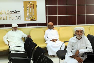 Men wait to collect Zakat donated by the public and distributed by the Zakat Fund in Abu Dhabi. The National