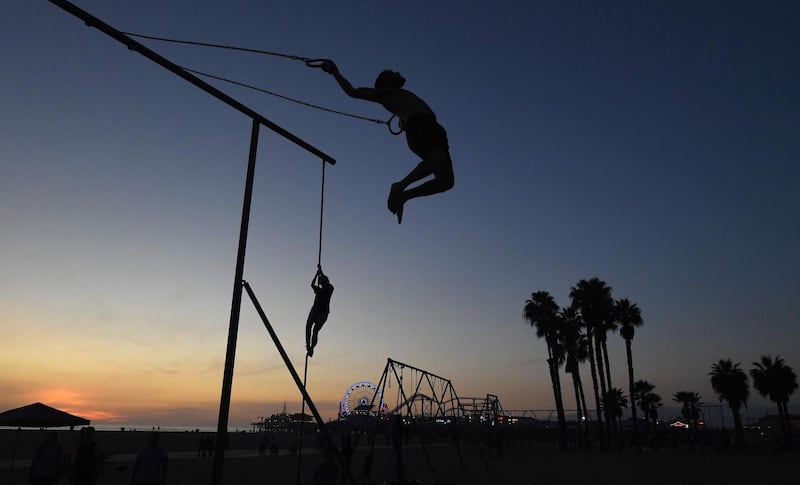 A gymnast performs on the rings as the sun sets at the original Muscle Beach in Santa Monica, California. Mark Ralston / AFP Photo