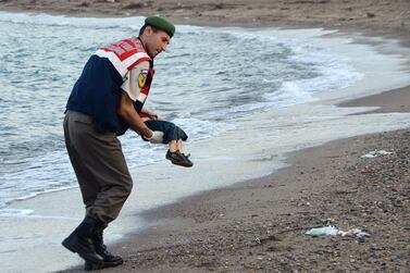 A Turkish police officer carries the body of Aylan Shenu off the shores of southern Turkey after a boat carrying refugees sank while reaching the Greek island of Kos. AFP