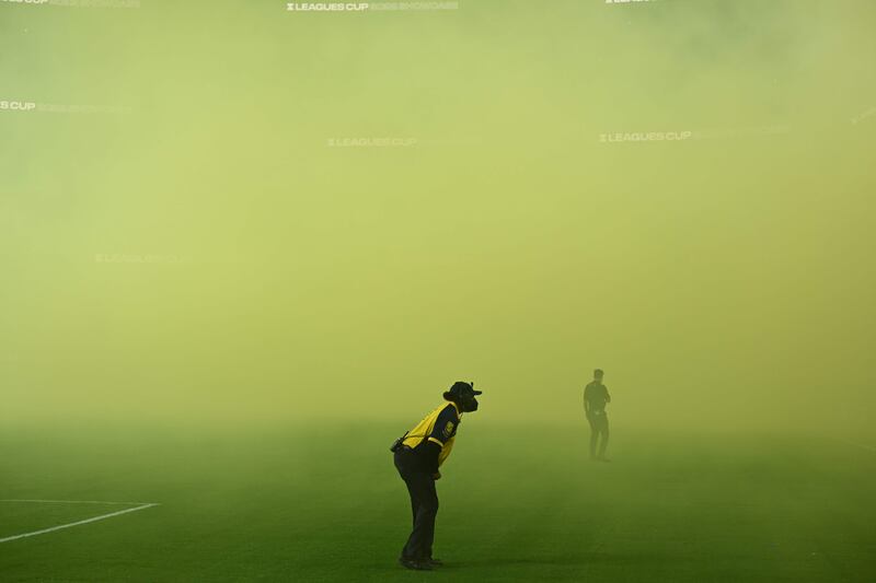 A security guard looks through the smoke at the start of the Leagues Cup friendly football match between USA's Los Angeles FC and Mexico's Club America at SoFi Stadium in Inglewood, California. AFP