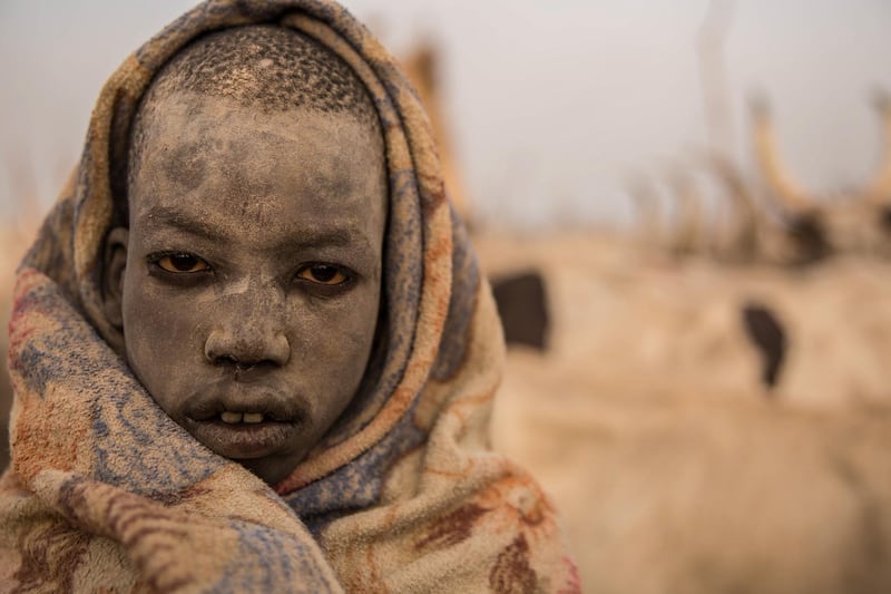 A Sudanese boy covers his face in ash from a burned cow dung to keep away mosquitos.