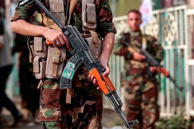 A fighter loyal to Yemen's Houthi rebels holds a Kalashnikov assault rifle showing a picture of other slain comrades as he stands guard during a rally commemorating the Shiite Muslim religious holiday of Ashura in the capital Sanaa. AFP