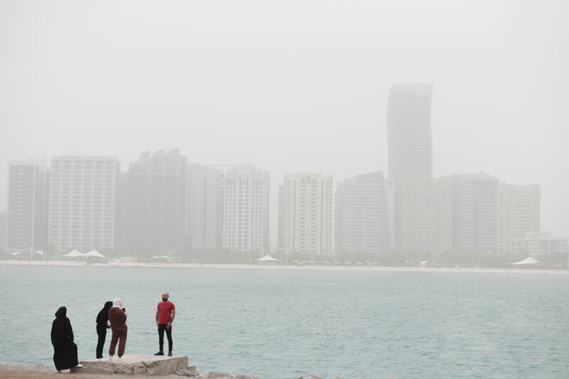 People take photos of the hazy skyline in Abu Dhabi. Khushnum Bhandari / The National
