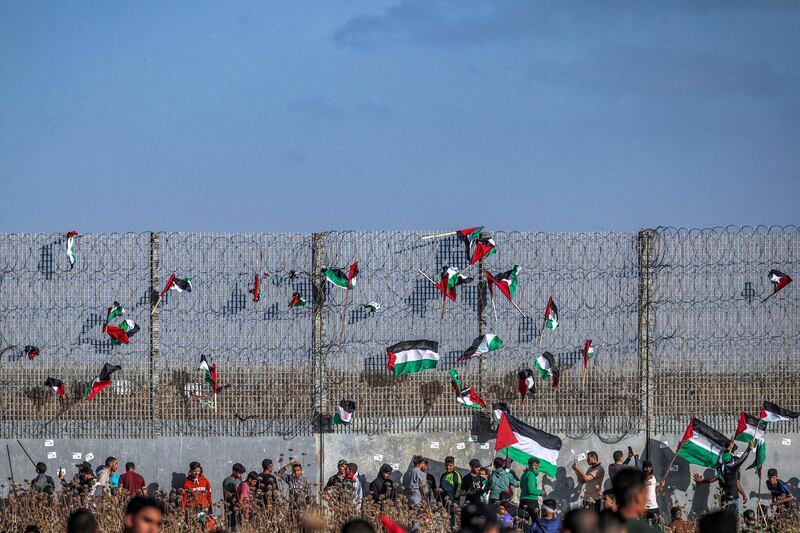 Palestinian flags are fixed to the barbed-wire border with Israel to the east of Gaza city during a demonstration against the Israeli Flag March. AFP
