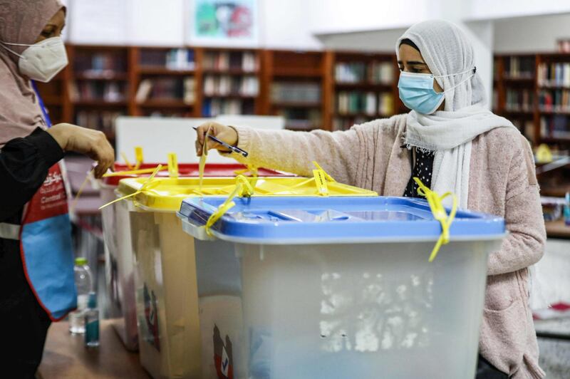 A mask-clad voter casts her ballot while voting in an election for the Tripoli Municipal Council, in Libya's capital on February 6, 2021.  / AFP / Mahmud TURKIA
