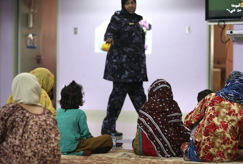 Women and their children eat lunch and spend their time together, as a correctional officer walks by.