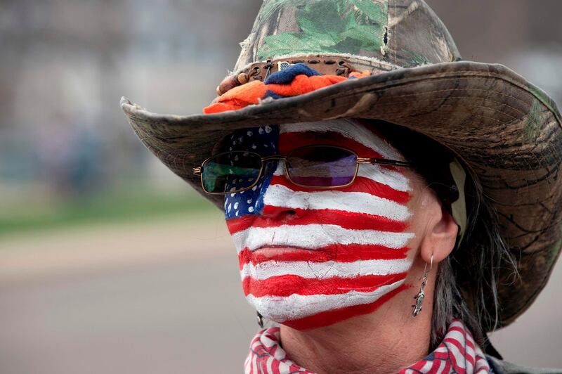 A woman with the US flag painted on her face gathers with others to protest coronavirus stay-at-home orders during a "ReOpen Colorado" rally in Denver, Colorado. AFP