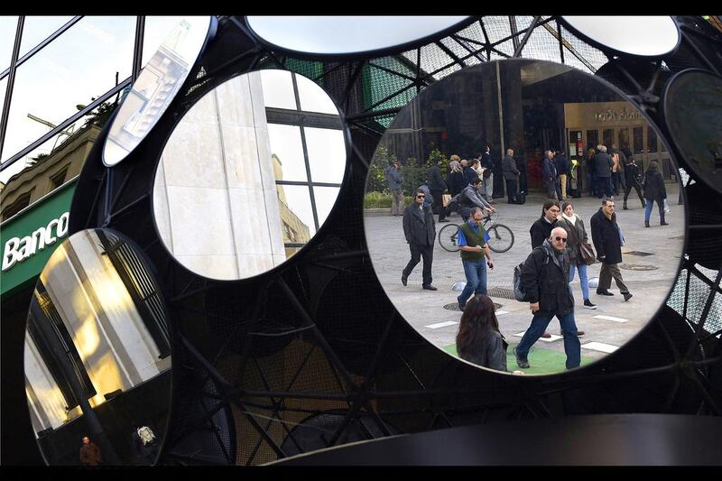 Passersby are reflected in a sculpture made out of mirrors in the financial district in Buenos Aires. Argentina has defaulted for the second time in 13 years after officials failed to come to an agreement with the country's bondholders. Daniel Garcia / AFP