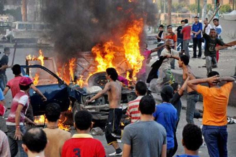 Egyptian protesters gather around a burning vehicle in downtown Cairo, Egypt, early Saturday.