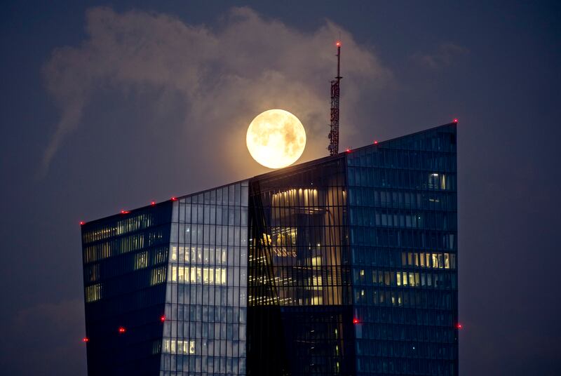 The moon sets behind the European Central Bank building in Frankfurt, Germany. AP