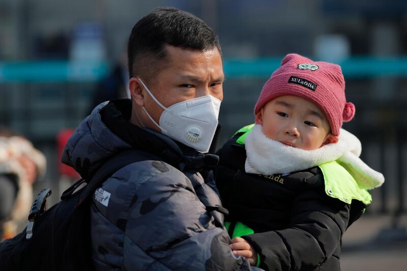 epa08161948 A Chinese man wears a mask while holding a child at Beijing Railway Station in Beijing, China, 25 January 2020. On 25 January, the National Health Commission of China confirmed the death toll from the Wuhan coronavirus outbreak has risen to 41 with 1,287 cases of patients infected as of 24 January.  EPA/WU HONG