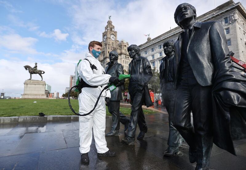 A man disinfects a statue of the Beatles in Liverpool. Reuters