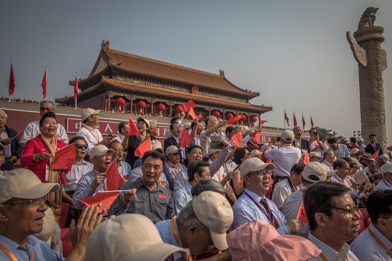 Visitors with Chinese flags sing at the military parade next to Tiananmen Square. EPA