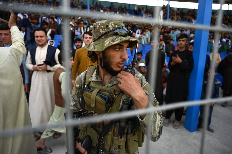 A Taliban fighter stands guard as spectators watch the Twenty20 cricket trial match in Kabul. AFP
