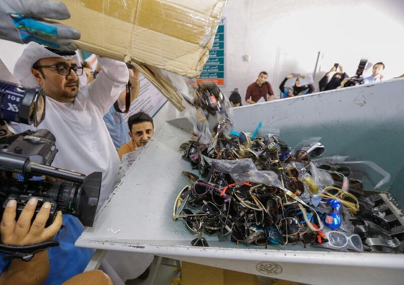 Ibrahim Behzad, director of the intellectual property protection division at DED, puts faker designer sunglasses through the shredding machine.  Victor Besa for The National