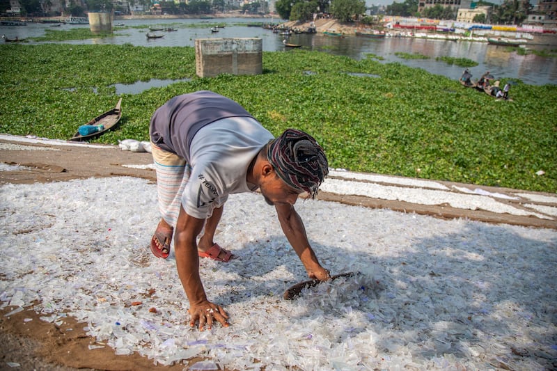 A man dries plastic chips at the Buriganga river in Dhaka, Bangladesh. EPA