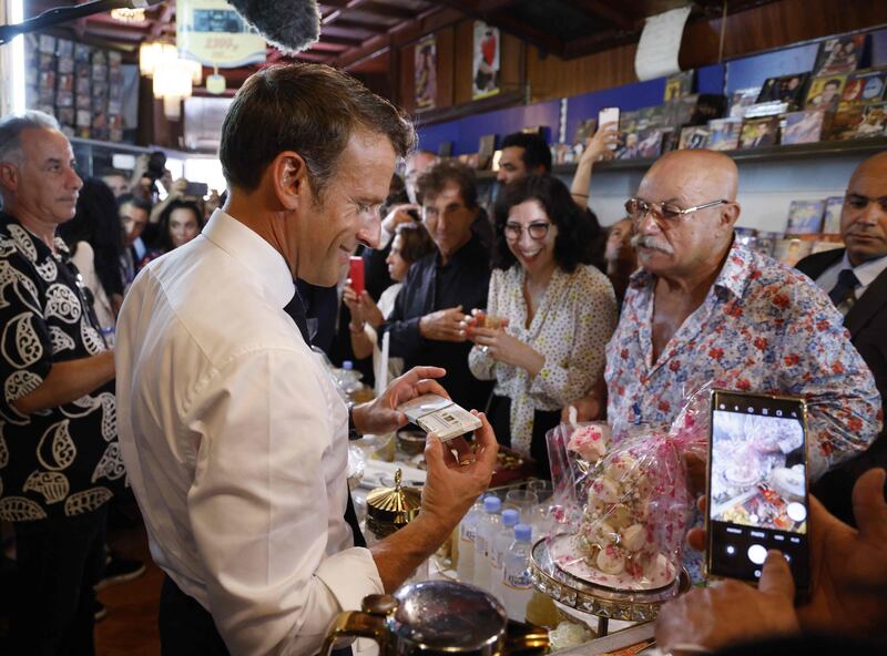 France's President Emmanuel Macron checks out an audio tape as Disco Maghreb owner Boualem Benhaoua and France's former culture minister and Arab World Institute President Jack Lang look on. AFP