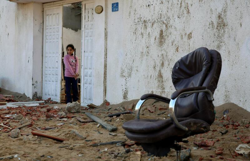 A Palestinian girl looks out from her family house at a damaged office in Hamas, Gaza City. AP Photo