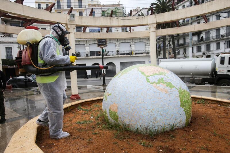 A worker wearing a protective suit disinfects a globe-shaped public statue in Algiers, Algeria. Reuters