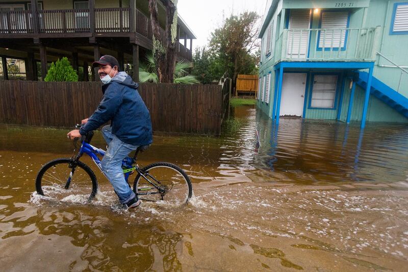 Rafael Juarez rides his bicycle through a street flooded by Tropical Storm Beta as he makes his way home from the store in Galveston, Texas. Houston Chronicle via AP