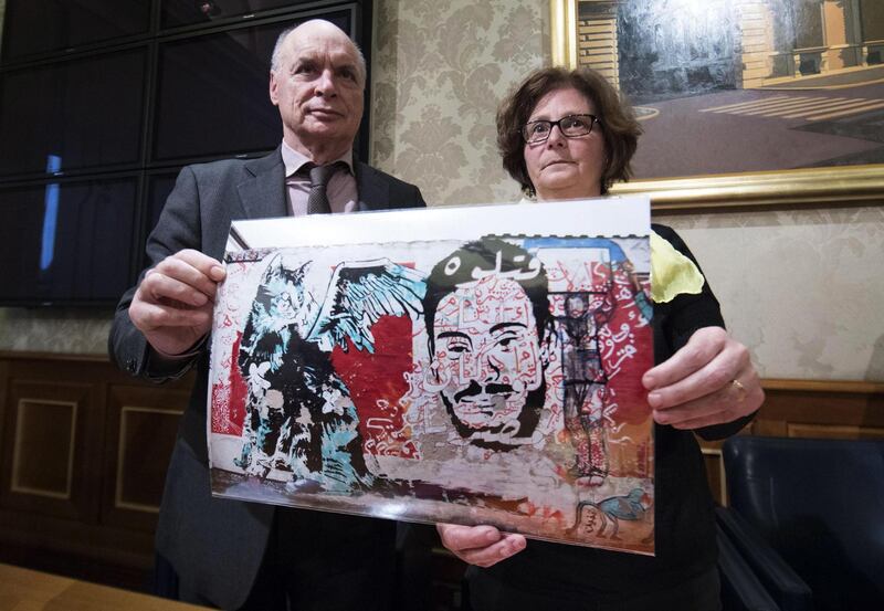 FILE - In this Monday, April 3, 2017 file photo, Giulio, left, and Paola Regeni, the parents of Giulio Regeni, an Italian graduate student tortured to death in Egypt, shows a pictures of a murales depicting their son as they meet the media during a press conference in Rome. (Massimo Percossi/ANSA via AP)