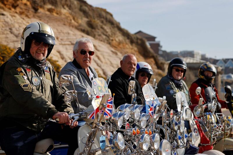 Rodney Hall, left, poses on his vintage Lambretta scooter after stopping at the beach with his friends and fellow members of the Breakfast Crew scooter club as they ride out for the first time in a group of six, in Bournemouth. AFP