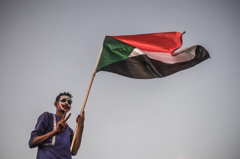 TOPSHOT - A Sudanese protestor waves a national flag during a protest outside the army complex in the capital Khartoum on April 20, 2019. Protest leaders are to hold talks on April 20 with Sudan's military rulers who have so far resisted calls to transfer power to a civilian administration, two leading figures in the protests told AFP. / AFP / OZAN KOSE
