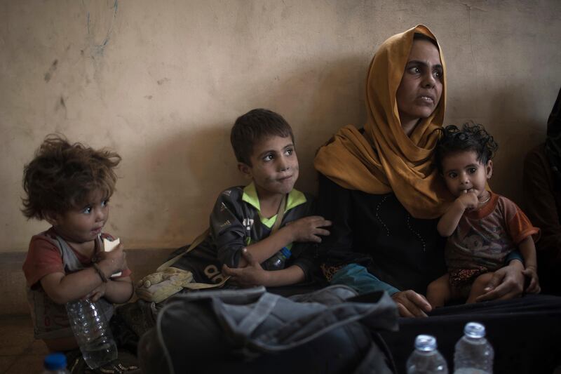 Iraqi civilians sit inside a house as they wait to be taken out of the Old City during fighting between Iraqi forces and ISIL militants in Mosul on Sunday. AP / Felipe Dana