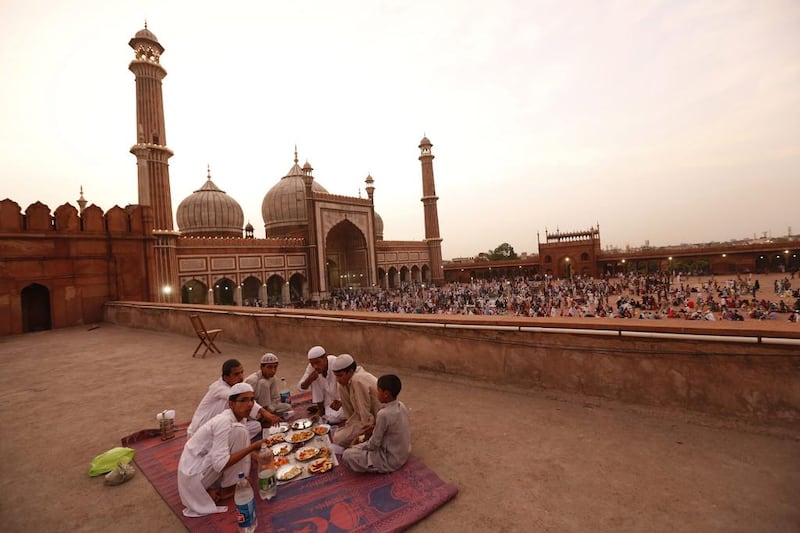 Families sit around large sheets of cloth spread out on the flagstones, so that the iftar meal seems almost like a picnic.  Harish Tyagi/EPA