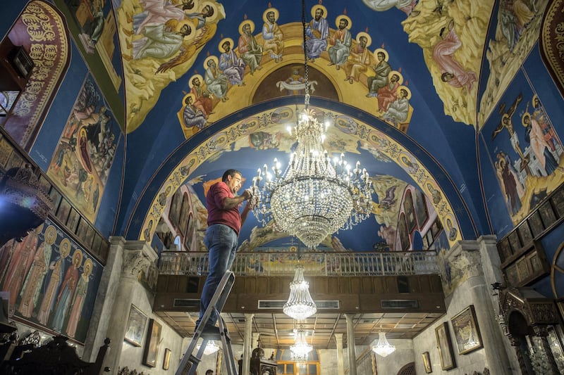 Rami Ayyad stands on a ladder as he carefully cleans each crystal from the chandelier hanging from the the ceiling of the Church of Saint Porphyrius in Gaza City on December 20,2018. The Greek Orthodox church dates back to the 12 century .(Photo by Heidi Levine for The National).