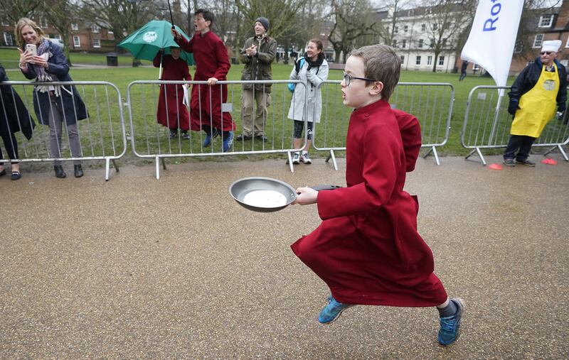A boy chorister of Winchester Cathedral takes part in the Shrove Tuesday pancake race on Tuesday. PA