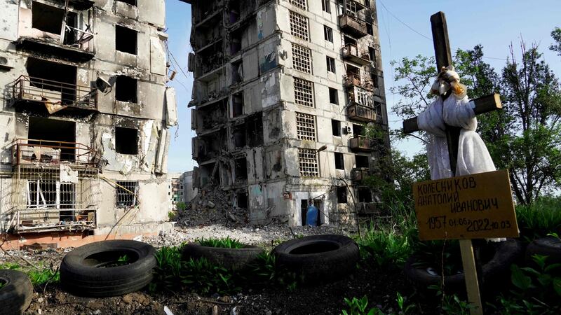 A grave in front of destroyed residential buildings in Mariupol. AFP