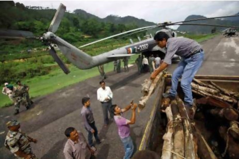Gauchar residents unload wood to be loaded onto an Indian air force helicopter bound for Kedarnath to construct a giant funeral pyre for flood victims.