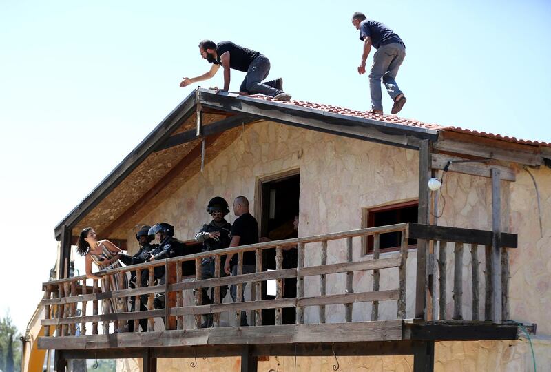 Israeli soldiers try to prize the Palestinian woman from the building. EPA