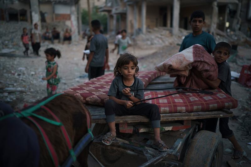 Chadi Nassir, 7, sits on a donkey cart as his brother, Mahmoud, loads it with belongings from their damaged house in Beit Hanoun. AP