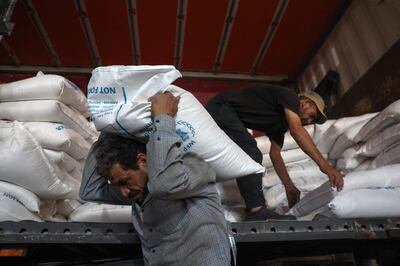 Workers unload bags of aid at a warehouse near the Bab Al Hawa border crossing with Turkey in July. AFP