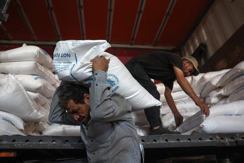 Workers unload bags of aid at a warehouse near the Syrian Bab Al Hawa border crossing with Turkey. AFP