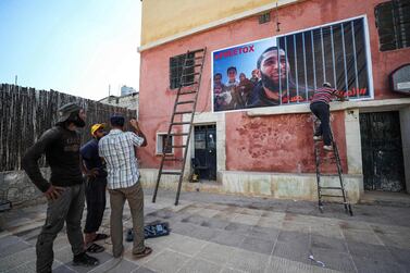 Men fix up a banner on the side of a building calling for the release of Tauqir Sharif, a self-described aid worker stripped of his British nationality and detained by Hayat Tahrir Al Sham (HTS) in Syria's rebel-held northwestern Idlib province. AFP