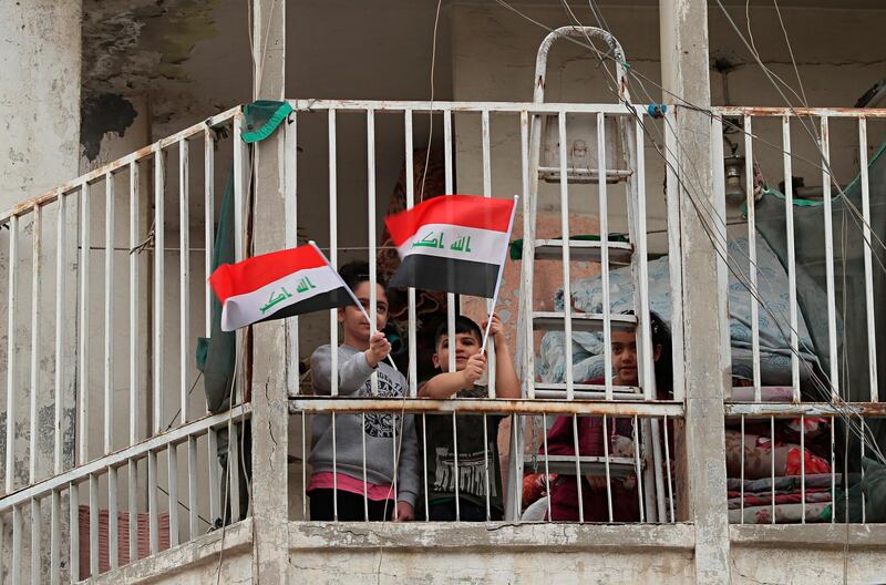Children wave national flags in solidarity with the families of those who have died or are ill with the coronavirus and support for doctors and nurses fighting to save them, in central Baghdad, Iraq. AP Photo